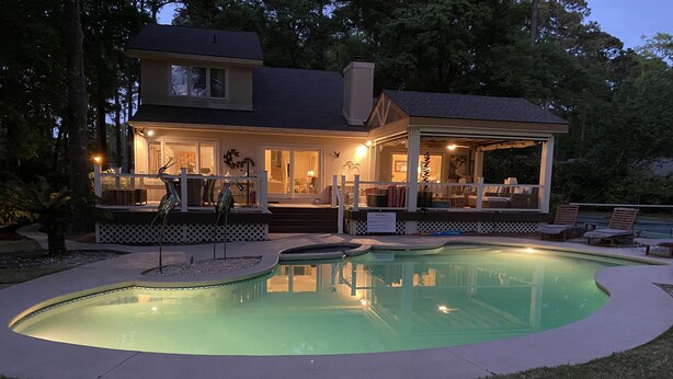 A house with a swimming pool, a covered patio, and a fenced deck area.