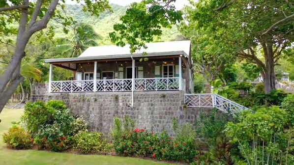 A stone building with a balcony, surrounded by lush greenery and trees.