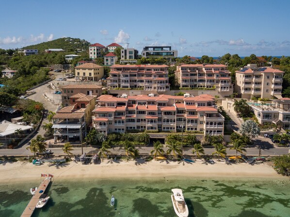 Un hotel frente a la playa con varias construcciones, una playa de arena y aguas turquesas cristalinas.