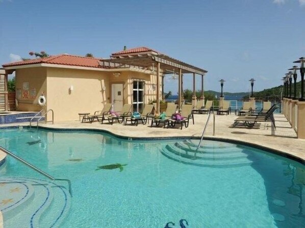 Uma área de piscina com espreguiçadeiras e um pequeno pavilhão.