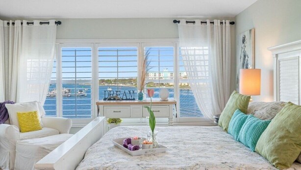 A bedroom with a bed, a desk, a chair, and a view of the sea. - Beautiful Views! Water front! Two Bedrooms and Two Baths with free wifi and beach equipment (Indian Rocks Beach)