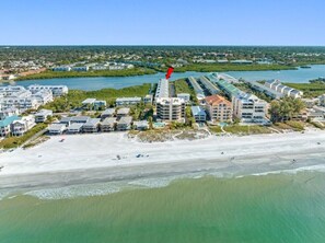 An aerial view of a coastal hotel area with beachfront properties, a marina, and a river.