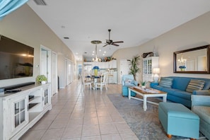 A spacious living area with a television, sofa, and coffee table, leading to a kitchen and dining area.