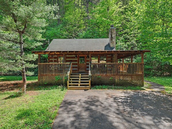 Eine kleine Holzhütte mit Veranda, Schornstein und Holzpforte.