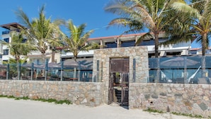A stone-walled building with a gated entrance, palm trees, and a clear blue sky. - Pietra Flat (Florianópolis)