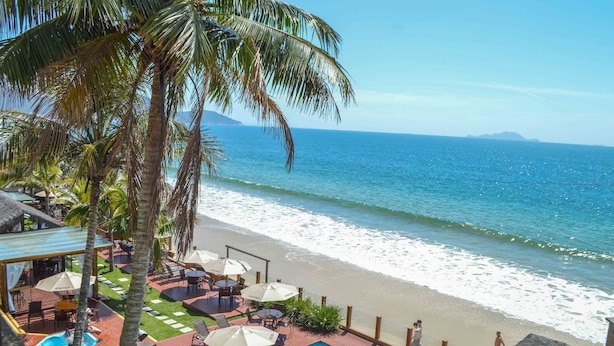 A beachside resort with a swimming pool, outdoor seating, and palm trees. - Pietra Flat (Florianópolis)