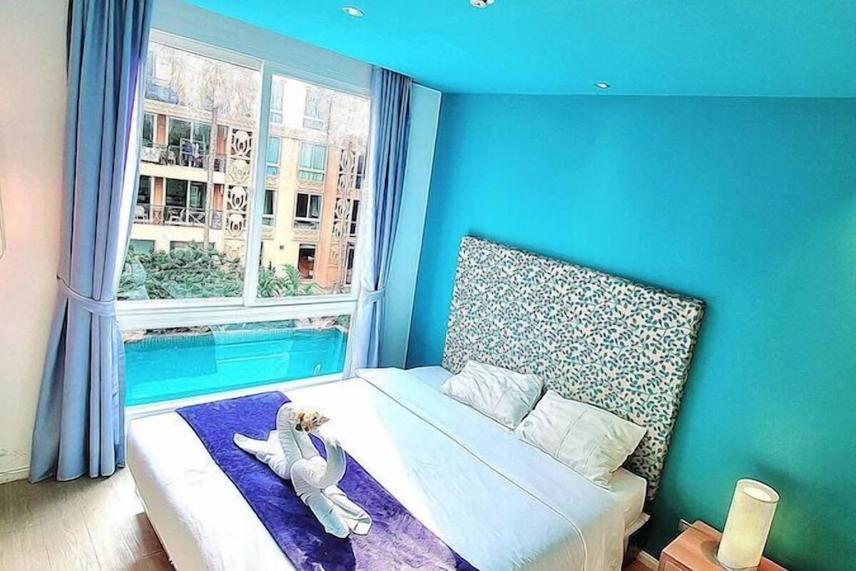Une chambre avec un grand lit, une vue sur un bâtiment à l’extérieur et un mur bleu.