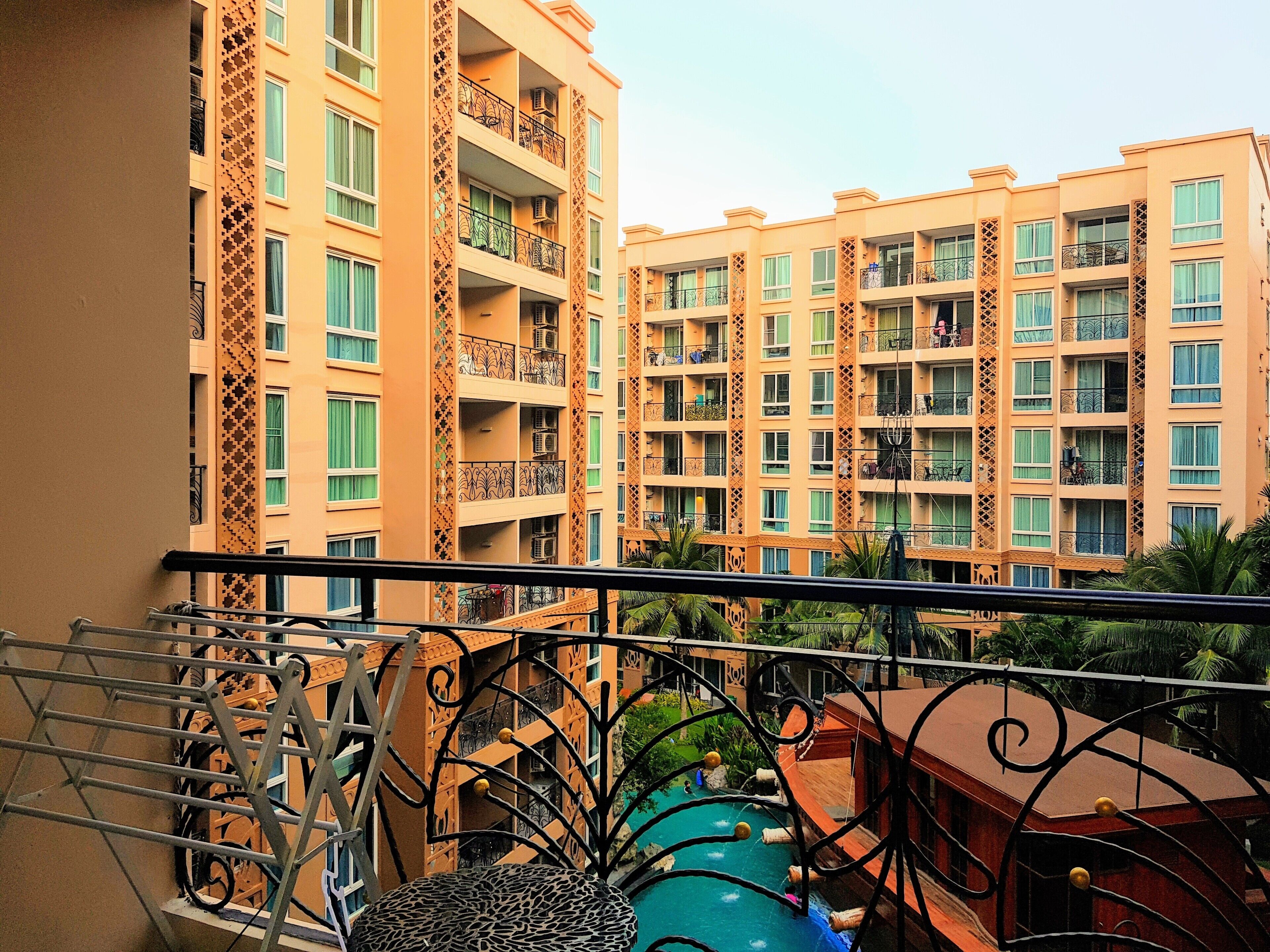 A multi-story residential building with balconies, a pool area, and a view of neighboring buildings.
