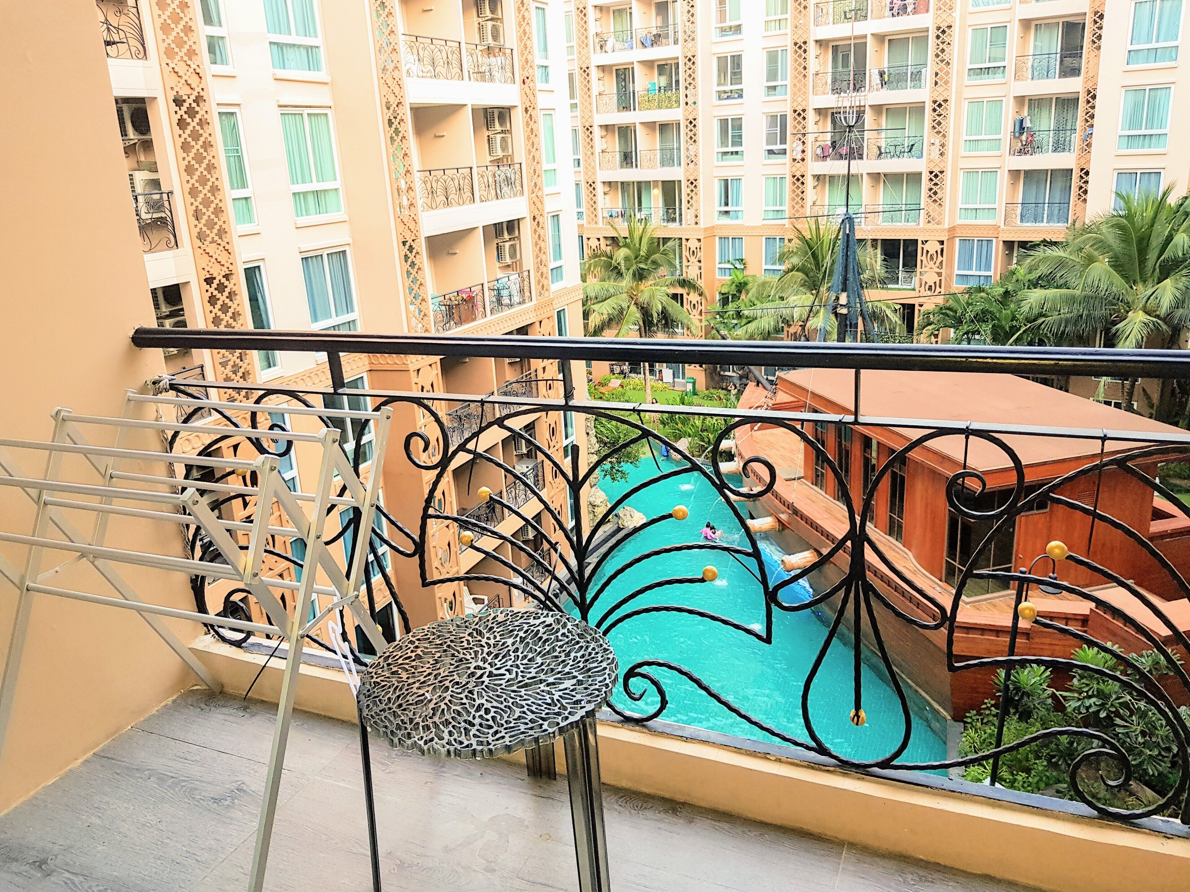 A balcony with a view of a swimming pool and adjacent buildings.