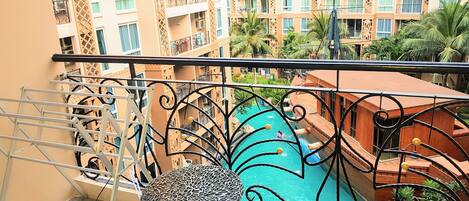 A balcony with a view of a swimming pool and adjacent buildings.