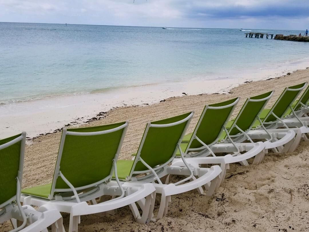 A row of green and white beach chairs facing the ocean.