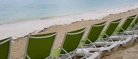 A row of green and white beach chairs facing the ocean.