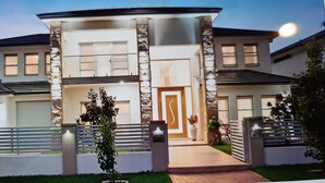 Une maison moderne à deux étages, dotée d’une entrée centrale, d’une allée et d’une pelouse bien entretenue.