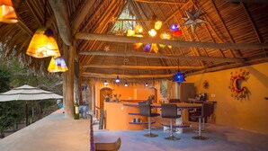 A restaurant with a thatched roof, hanging lights, and bar stools. - Lux in Yelapa, Infinity Pool, Huge Views, AC, Accommodates 8 to 10 (Yelapa)