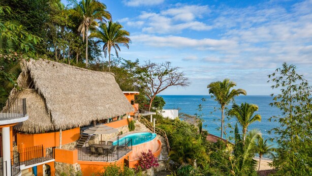A resort with a thatched-roof building, a pool, and a view of the ocean. - Lux in Yelapa, Infinity Pool, Huge Views, AC, Accommodates 8 to 10 (Yelapa)