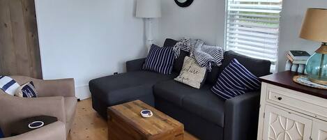 Een woonkamer met een bank, fauteuil, houten salontafel en een kast.