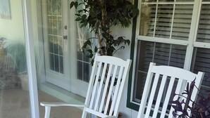 Een terras met witte schommelstoelen en een plant in pot.