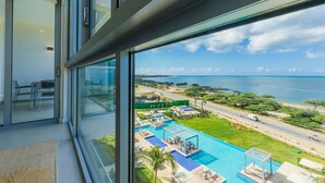 Ein modernes Hotelzimmer mit großem Fenster, das einen Blick auf einen Pool und die Küste bietet.