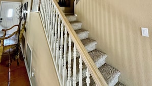 A staircase with white balusters and carpeted steps, leading to a landing with a framed artwork. - Charming Southwest Style Vacation Home  (Phoenix)
