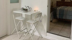 Habitació petita amb un llit, un escriptori amb dues cadires, un rètol fixat a la paret que diu 'love' i un ventilador de sostre.