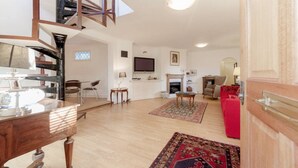 A spacious living room with a high ceiling, a fireplace, a television, and a red sofa. - Spacious Family House in Barnes, 30 Minutes from Downtown London (London)