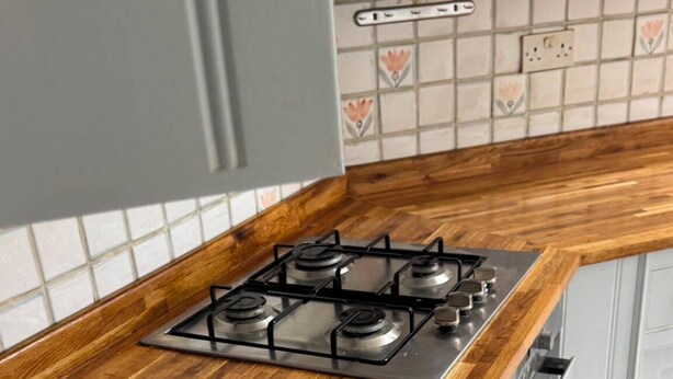 A kitchen with a wooden countertop, a gas stove, and white cabinets. - Spacious Family House in Barnes, 30 Minutes from Downtown London (London)