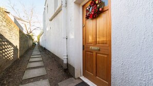 A narrow alleyway leading to a wooden door with a wreath. - Spacious Family House in Barnes, 30 Minutes from Downtown London (London)