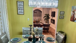 A dining area with a table set for four, a chandelier, and a kitchen visible in the background. - Atlanta Pool Home Near Airport, Near Airport 8 guests Max (Atlanta)