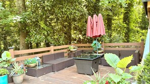 An outdoor patio with wicker furniture, a glass-top table, and a wooden deck. - Atlanta Pool Home Near Airport, Near Airport 8 guests Max (Atlanta)