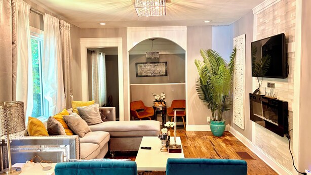 A living room with a sofa, a coffee table, a TV, and a plant. - Atlanta Pool Home Near Airport, Near Airport 8 guests Max (Atlanta)