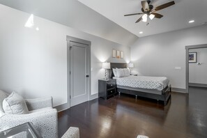 A bedroom with a bed, bedside tables, a ceiling fan, and a door.