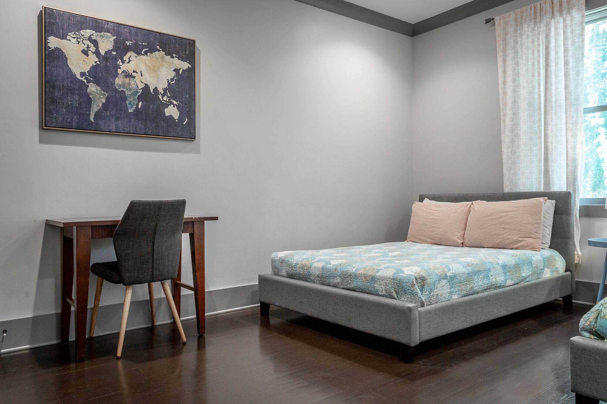Um quarto com uma cama, uma escrivaninha e uma cadeira.