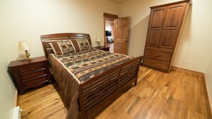 Une chambre à coucher avec un lit en bois, des tables de chevet, une commode et une armoire.