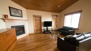 Un salon avec une cheminée, un plancher en bois, un téléviseur et un canapé.