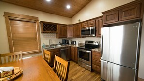 Une cuisine avec des meubles en bois, des appareils électroménagers en acier inoxydable et une table à manger avec des chaises.