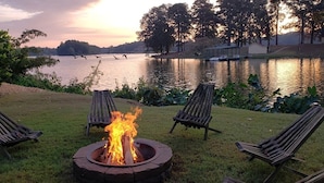 Un patio junto al lago con un hogar a leña y sillones de descanso.