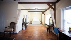 Un dormitorio con una cama grande, vigas de madera, una silla y un escritorio.