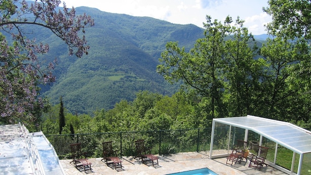 Une piscine avec vue sur les montagnes, entourée de chaises longues et d’un espace salon abrité.