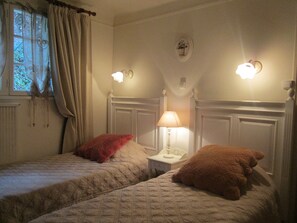 Une chambre avec deux lits, chacun étant équipé d’un oreiller et d’une table de chevet avec une lampe.