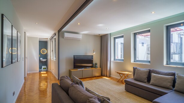 Una sala de estar moderna con un sofá, televisor y vistas al exterior.