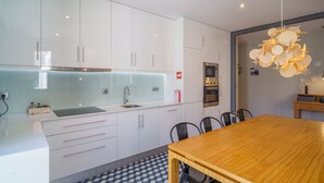 Una cocina moderna con armarios blancos, una mesa de comedor de madera y una lámpara colgante original.