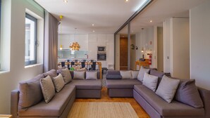 Una sala de estar moderna con un sofá modular, un comedor y una cocina al fondo.