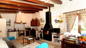 Een gezellige woonkamer met een open haard, een eethoek met een tafel voor twee en een keuken met moderne apparatuur.