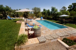 Un jardin avec une piscine, des chaises longues et un espace barbecue.