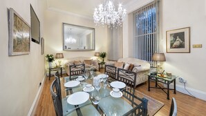 En matplats med ett glasbord för fyra personer, en soffa och en kristallkrona.