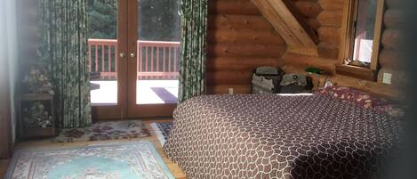 Une chambre dans une cabane en rondins, avec un lit, un tapis et une fenêtre avec des rideaux.