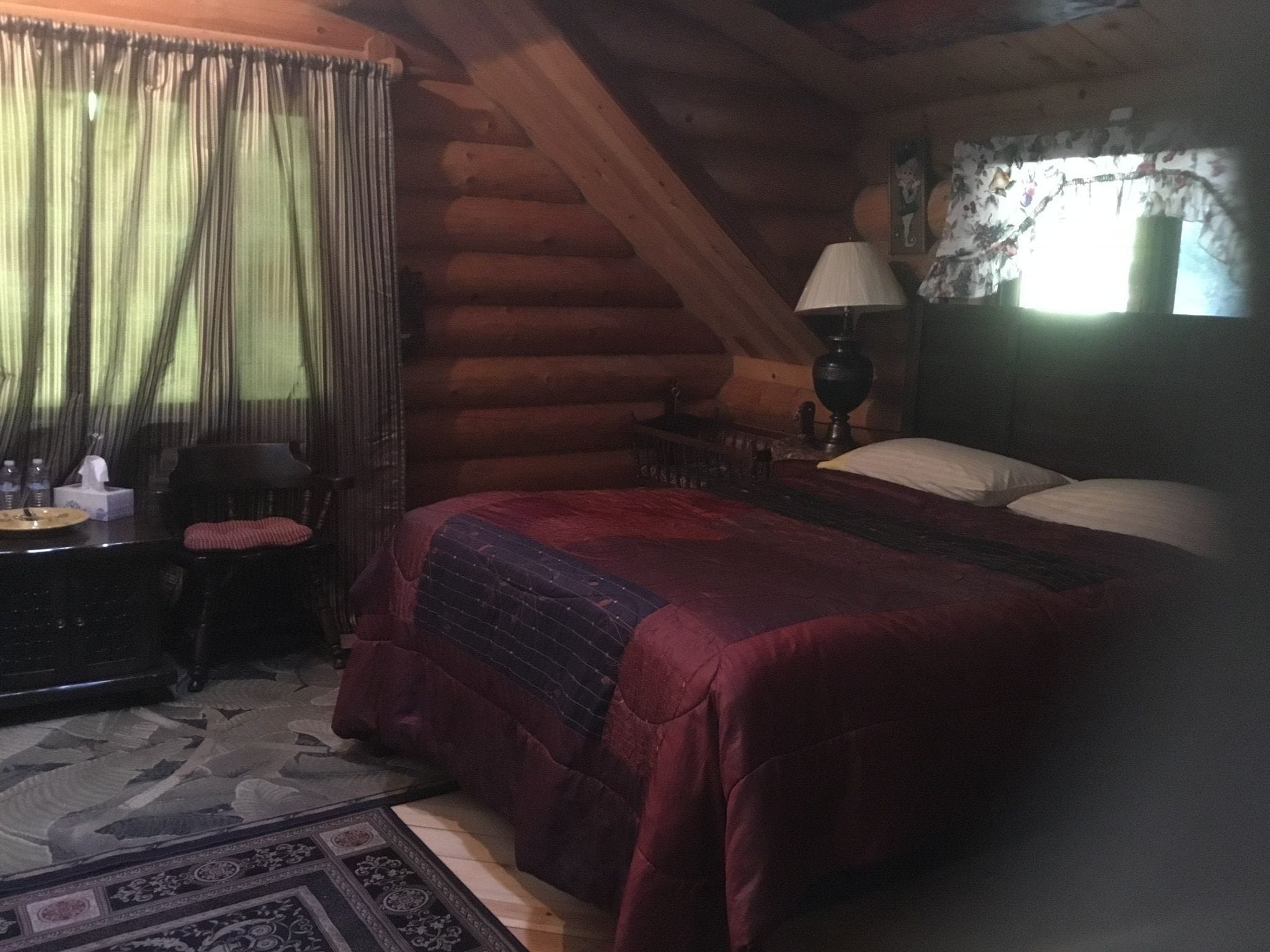 A log cabin room with a bed, a desk, and a chair.
