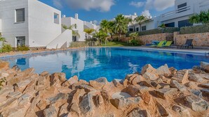 A modern pool area with a clear blue pool, surrounded by white buildings and palm trees. - Beautiful contemporary Villa (Orihuela)