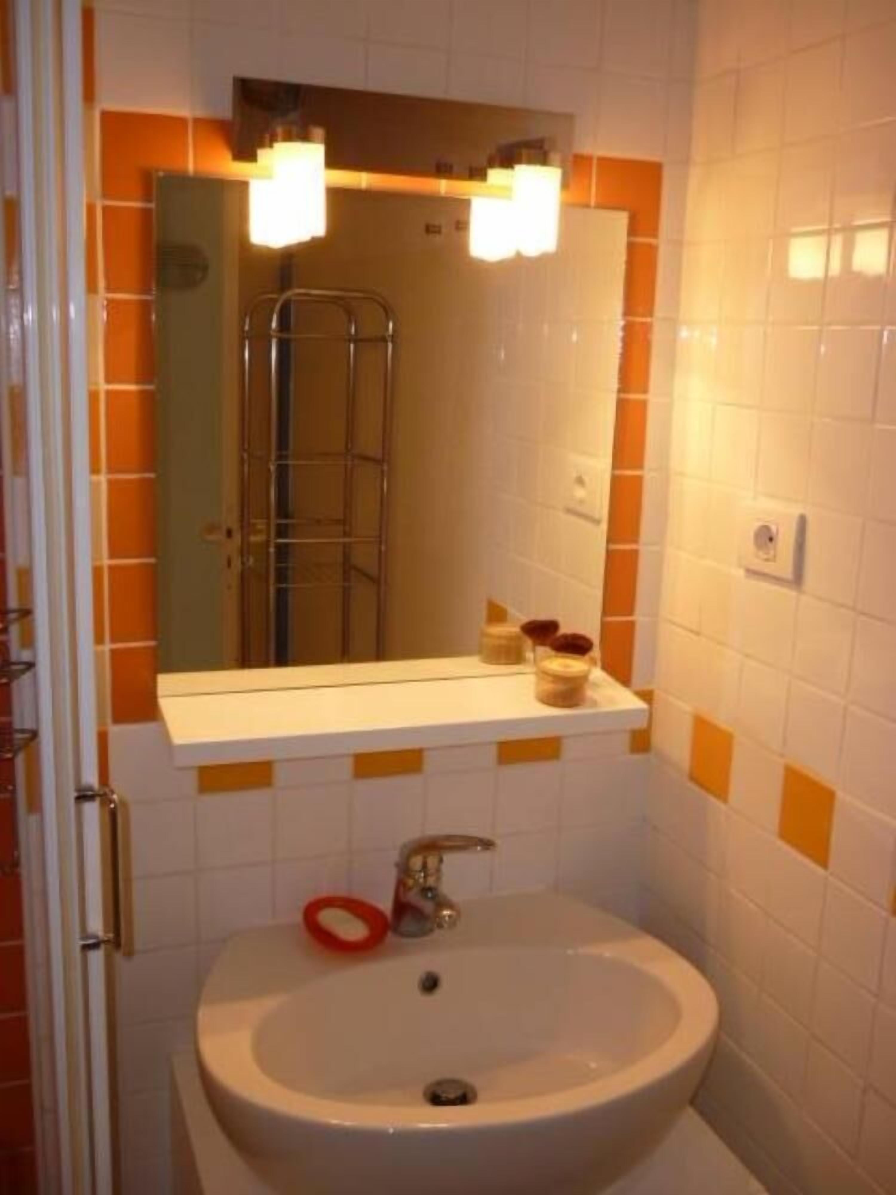 A bathroom with a white sink, a mirror above it, and a shower visible in the background.