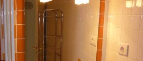 A bathroom with a white sink, a mirror above it, and a shower visible in the background.